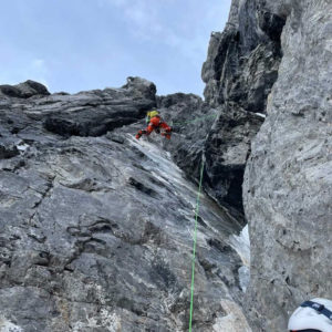 Kletterer in Schutzausrüstung an einer steilen Felswand in alpiner Umgebung